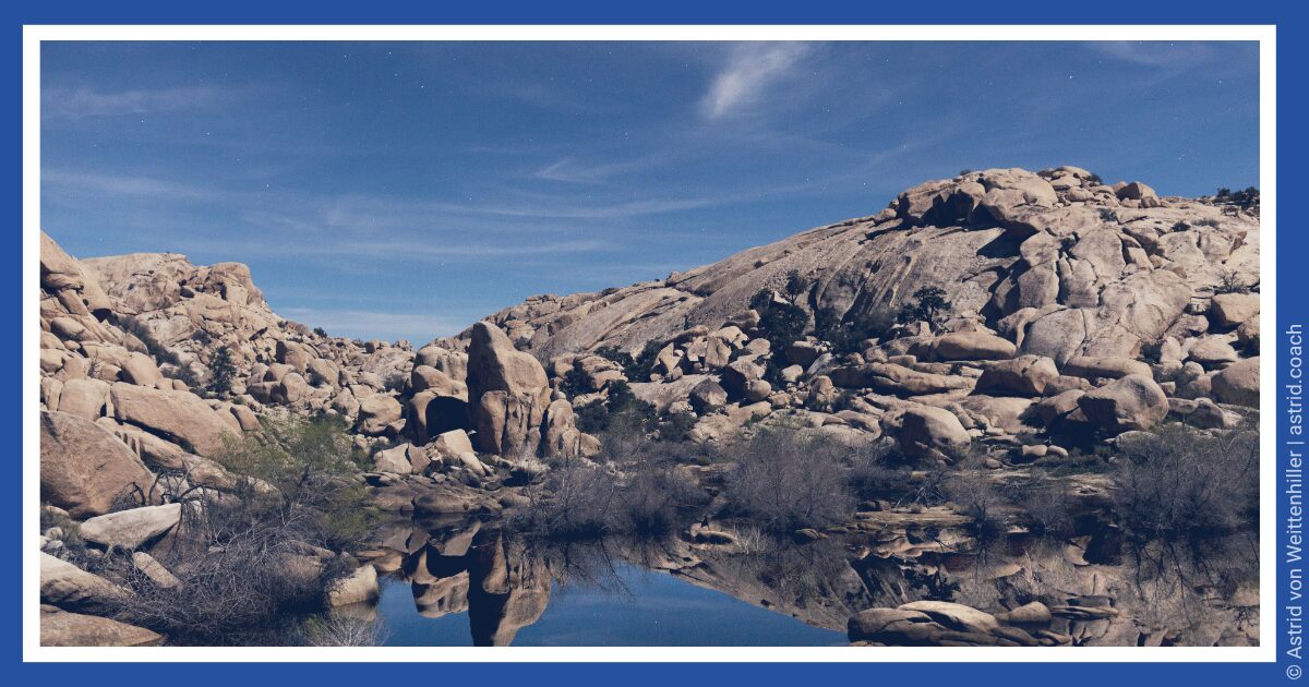 Felslandschaft mit ruhiger Wasserspiegelung unter blauem Himmel. | Rocky landscape with a calm water reflection under a blue sky.